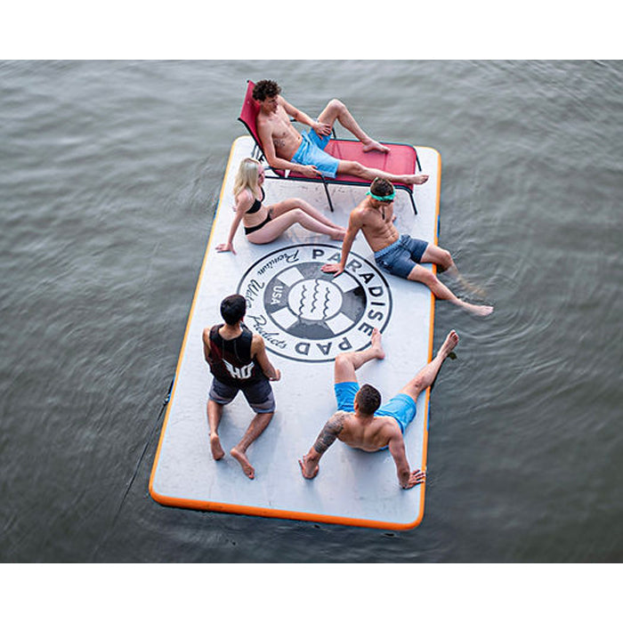 Paradise Pad 6'x13' Inflatable Water Mat with a group of 5 people hanging out on top, one of them resting on a sunbathing chair.